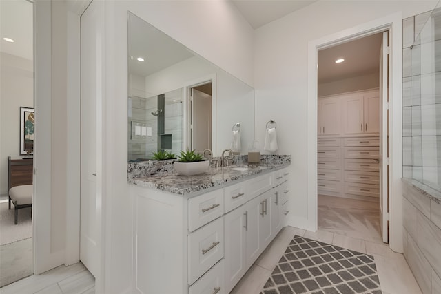 bathroom with tile patterned flooring, a tile shower, and vanity