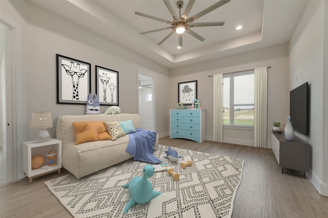 interior space featuring a raised ceiling, ceiling fan, and light hardwood / wood-style floors