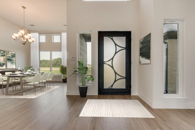 entrance foyer featuring a towering ceiling, an inviting chandelier, and wood-type flooring