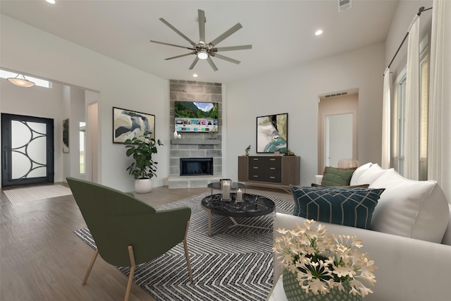 living room featuring a tiled fireplace, ceiling fan, and hardwood / wood-style floors