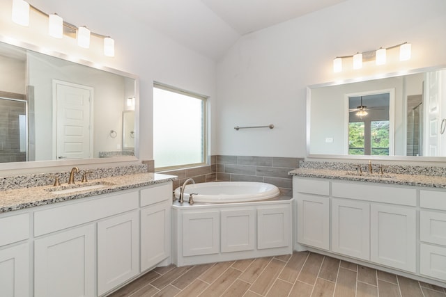 bathroom featuring lofted ceiling, vanity, ceiling fan, and a bathtub