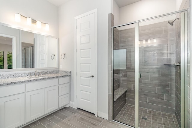 full bathroom featuring wood finish floors, vanity, and a shower stall