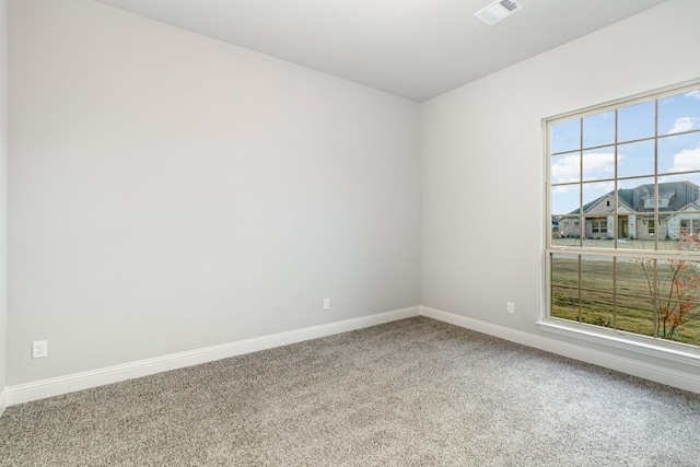 empty room featuring carpet, visible vents, and baseboards