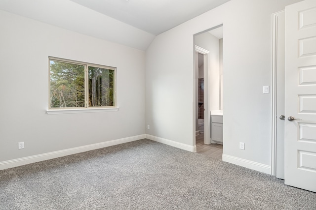 interior space with lofted ceiling, light carpet, and ensuite bathroom