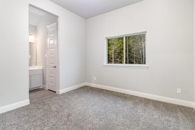 unfurnished bedroom featuring light colored carpet and ensuite bathroom