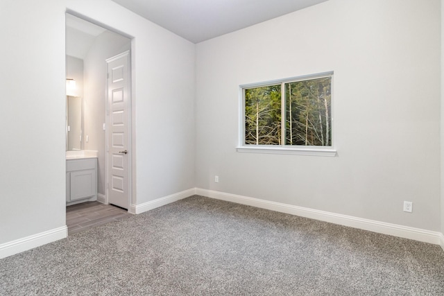 unfurnished bedroom with light colored carpet, connected bathroom, and baseboards