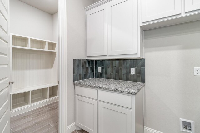 kitchen featuring white cabinetry, backsplash, light stone counters, and light hardwood / wood-style flooring