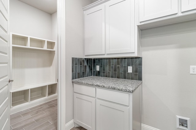 kitchen with open shelves, backsplash, wood tiled floor, white cabinets, and light stone countertops