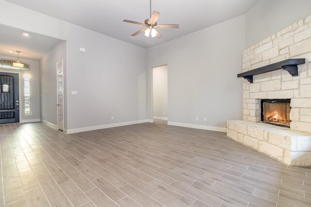 unfurnished living room featuring a stone fireplace, light wood-type flooring, and ceiling fan