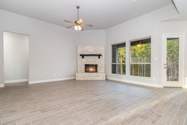 unfurnished living room with light wood-type flooring, a fireplace, ceiling fan, and plenty of natural light