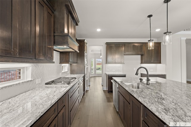 kitchen with pendant lighting, dark wood-type flooring, premium range hood, backsplash, and sink