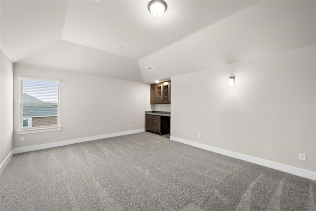 unfurnished living room with carpet flooring and vaulted ceiling