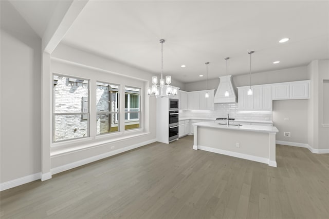 kitchen with custom exhaust hood, white cabinets, light countertops, and pendant lighting