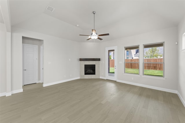 unfurnished living room with baseboards, a tile fireplace, visible vents, and light wood-style floors