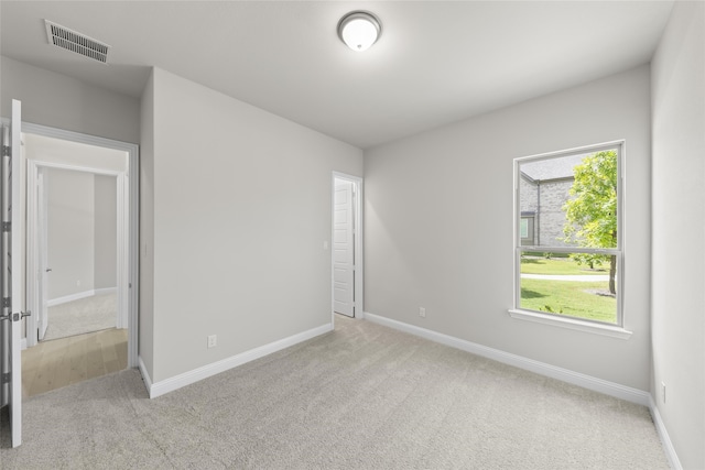 spare room with baseboards, visible vents, and light colored carpet