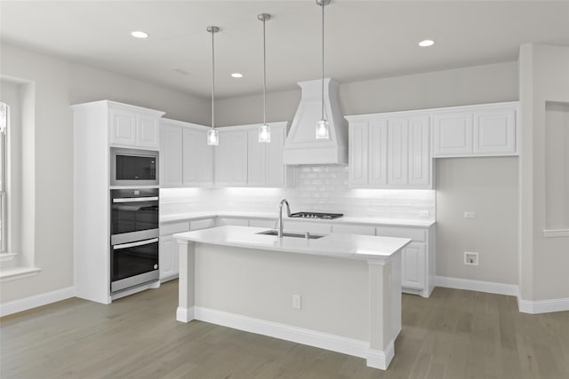 kitchen featuring light countertops, white cabinetry, a kitchen island with sink, and custom range hood