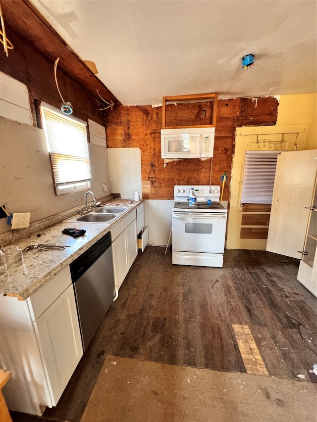 kitchen featuring white appliances, white cabinetry, wood walls, and dark hardwood / wood-style floors