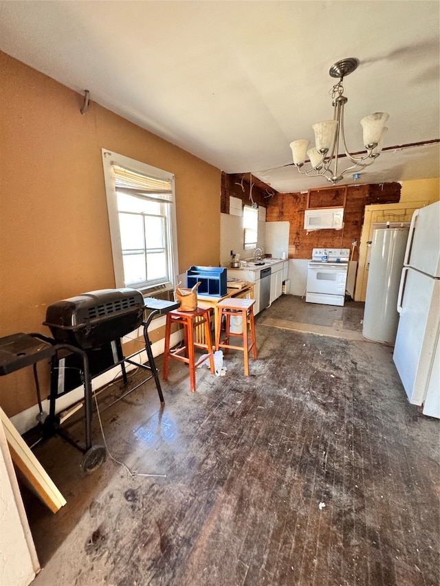 kitchen with white cabinets, sink, white appliances, a notable chandelier, and dark hardwood / wood-style flooring