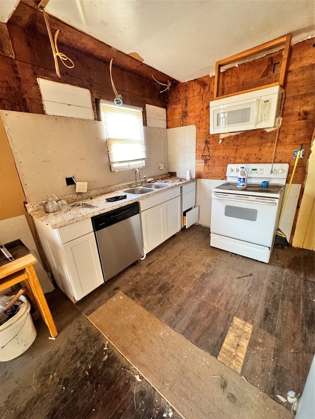 kitchen with white cabinetry, dark wood-type flooring, white appliances, wood walls, and sink