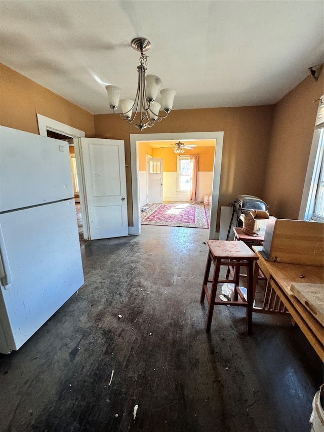 unfurnished dining area featuring ceiling fan with notable chandelier