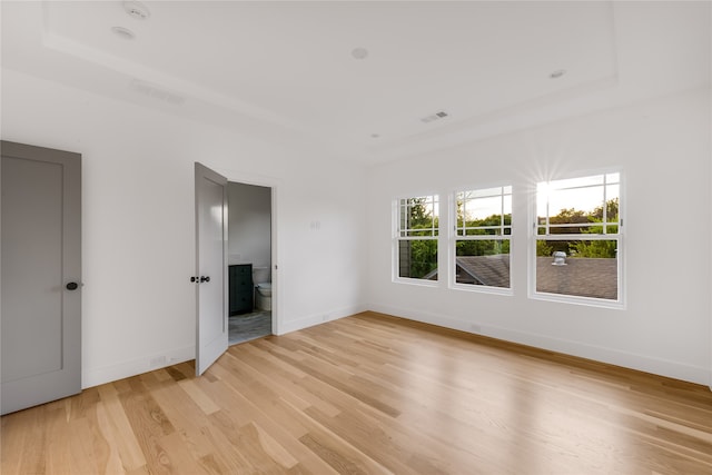 unfurnished living room with a raised ceiling and light hardwood / wood-style flooring