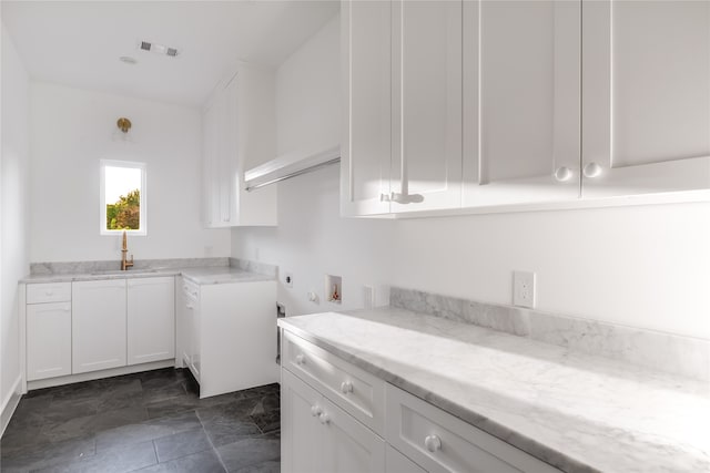 laundry area with cabinets, dark tile patterned flooring, washer hookup, electric dryer hookup, and sink