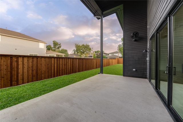 patio terrace at dusk featuring a yard