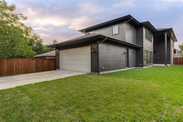 property exterior at dusk featuring a garage and a yard