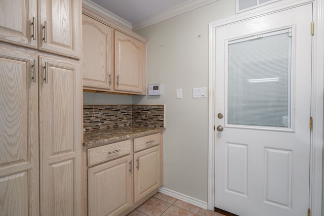 kitchen with light stone counters, tasteful backsplash, light tile patterned flooring, crown molding, and light brown cabinetry