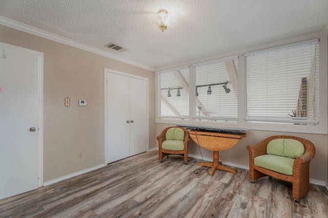 living area with a textured ceiling, hardwood / wood-style flooring, and crown molding