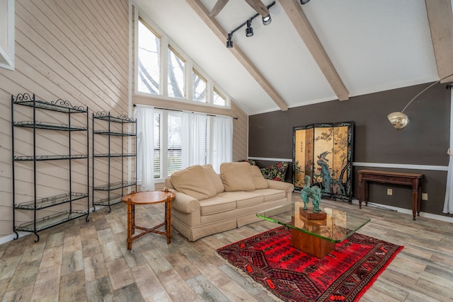 living room with wood-type flooring, beamed ceiling, wooden walls, and high vaulted ceiling