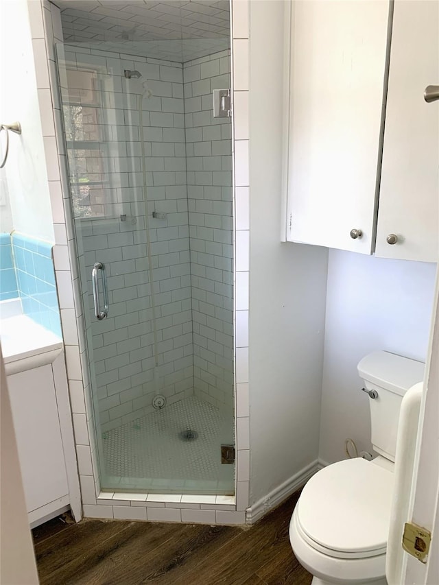 bathroom featuring wood-type flooring, a shower with door, and toilet