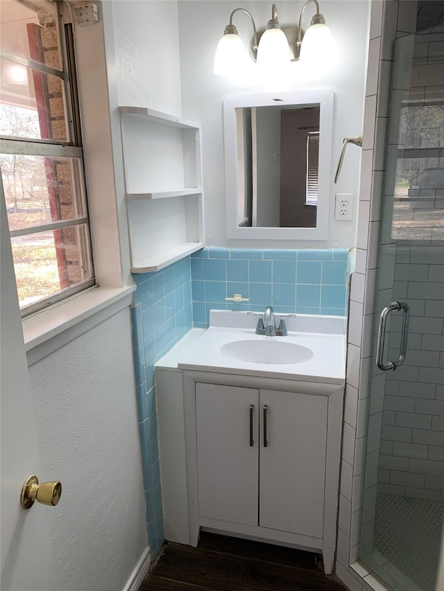 bathroom featuring vanity, a shower with shower door, and tile walls