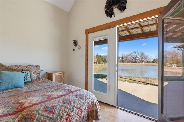 bedroom featuring light wood-type flooring, access to outside, vaulted ceiling, and a water view