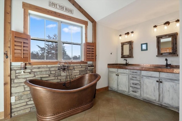 bathroom featuring lofted ceiling, a tub to relax in, vanity, and tile patterned flooring