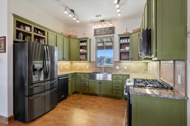 kitchen featuring sink, stainless steel appliances, light stone countertops, green cabinetry, and decorative backsplash