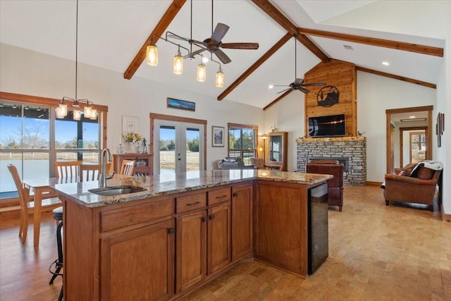 kitchen with a stone fireplace, a kitchen island with sink, sink, and decorative light fixtures