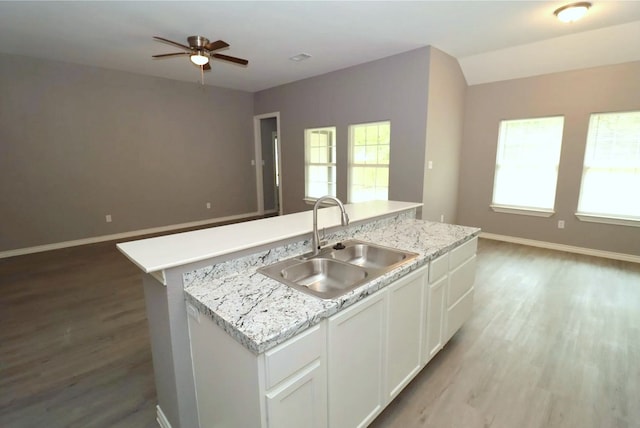 kitchen with ceiling fan, sink, light hardwood / wood-style flooring, a center island with sink, and white cabinets