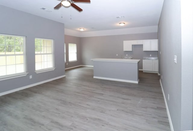 kitchen featuring light hardwood / wood-style floors, white cabinetry, ceiling fan, and a kitchen island