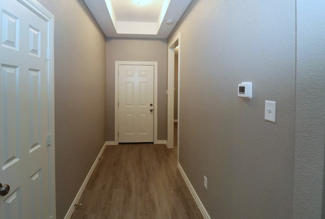 corridor with wood-type flooring and a raised ceiling