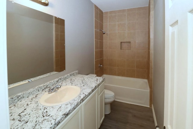 full bathroom with hardwood / wood-style floors, vanity, toilet, and tiled shower / bath