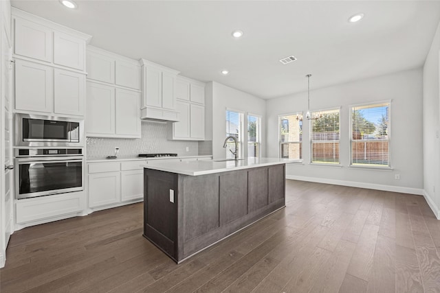 kitchen featuring dark wood-type flooring, sink, decorative light fixtures, white cabinetry, and stainless steel appliances