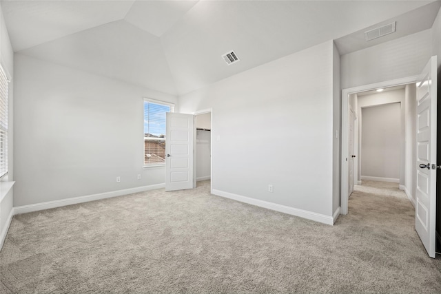 unfurnished bedroom with light colored carpet and lofted ceiling