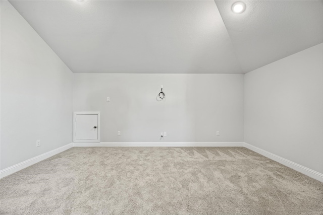 carpeted spare room with vaulted ceiling