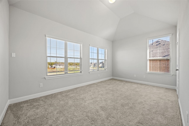 carpeted empty room featuring a wealth of natural light and vaulted ceiling