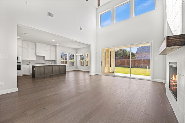 unfurnished living room featuring a high ceiling, dark hardwood / wood-style flooring, ceiling fan, and sink