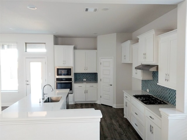 kitchen featuring appliances with stainless steel finishes, a kitchen island with sink, tasteful backsplash, and sink