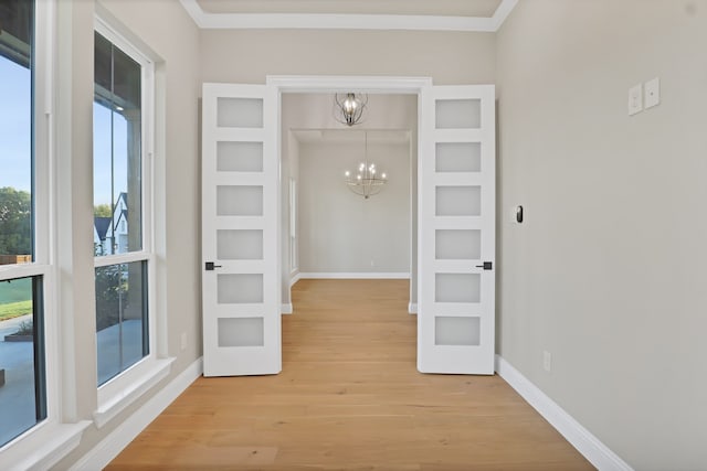 interior space featuring light hardwood / wood-style floors, a chandelier, and ornamental molding