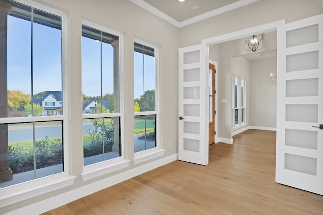 interior space with crown molding, light wood-type flooring, a chandelier, and a wealth of natural light