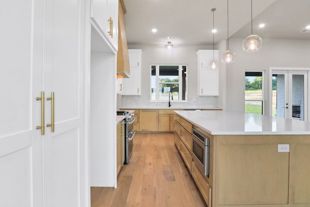 kitchen with stainless steel appliances, a healthy amount of sunlight, a kitchen island, and white cabinetry